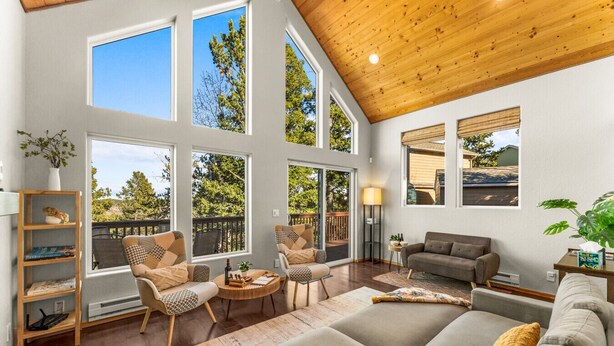 A spacious living room with large windows, a wooden ceiling, and a cozy seating area. - Epic Views, Modern Cabin, Hot tub, Family & Pets (Woodland Park)