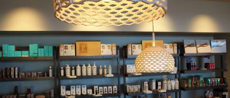 A retail store with shelves stocked with various products, a decorative hanging light fixture, and framed certificates or awards on the wall.