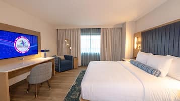 Habitación de hotel con una cama grande, un escritorio con computadora, un televisor y una silla.