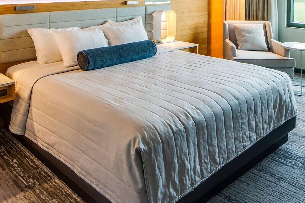Ein Hotelzimmer mit einem großen Bett, einem Sessel, einem Nachttisch und einer Lampe.