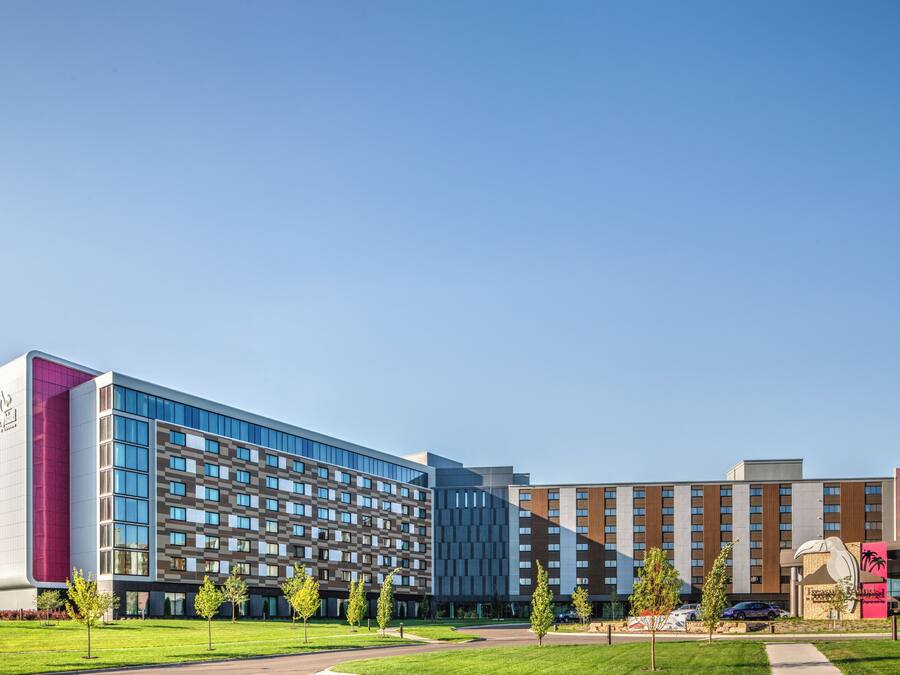 Un hotel moderno con varias construcciones, un patio central y una gran escultura.