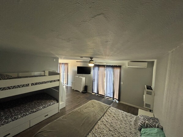 Une chambre de taille réduite avec des lits superposés, une petite kitchenette et un téléviseur.