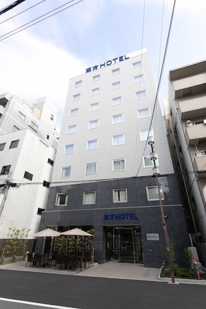 A hotel with a modern facade, multiple floors, and a ground-level entrance with outdoor seating. - Toho Hotel Namba Motomachi (Osaka)