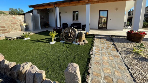 Une maison moderne dotée d’un patio couvert, de murs en pierre et d’une pelouse bien entretenue.