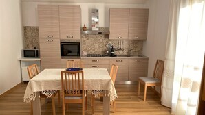 Une cuisine compacte dotée de meubles en bois, d’un four à micro-ondes, d’une cuisinière et d’un coin repas avec une table et des chaises.