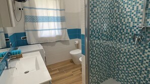 Une salle de bain équipée d’une douche, de toilettes, d’un lavabo et d’un miroir.