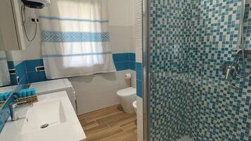 A bathroom with a shower, toilet, sink, and a mirror.