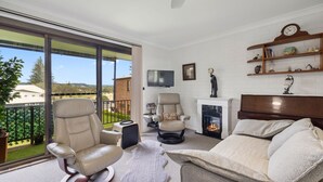 A living room with a fireplace, a TV, and a balcony with a view of a building labeled "WSLSC".