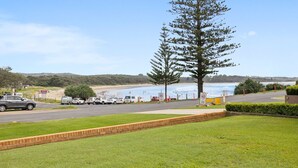 A parking area with vehicles, a road sign indicating a speed limit of 40, and a view of the beach and ocean.