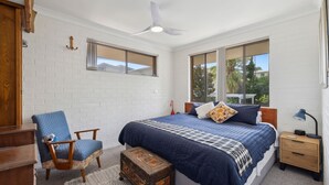A bedroom with a large bed, a chair, a nightstand, and a ceiling fan.