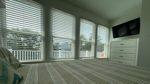 A bedroom with a bed, a dresser, and a TV mounted on the wall. - “Crescent Moon” - 5BR – established, top rated, dog friendly, 5 min walk to beach! (Folly Beach)