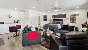 Ein modernes Hotelzimmer mit Bett, einer Sitzecke mit Sofa und Couchtisch, einer Küchenzeile und einem Badezimmer.