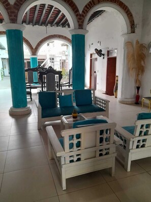 Amplio espacio interior con mobiliario blanco y detalles azules, que incluye suelo de baldosas y techos de ladrillo abovedados.