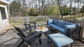 Eine Terrasse mit einer Couch, zwei Stühlen und einem kleinen Tisch.