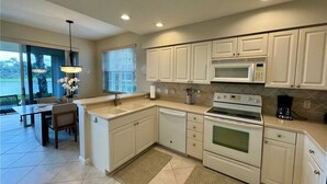 A modern kitchen with white cabinetry, a built-in microwave, and a stove. - Beautiful Relaxing condo with a Lake/Golf Course view 8 miles from beach! (Fort Myers)