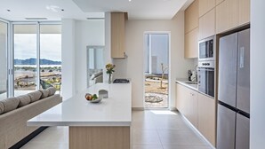 A modern kitchen with a central island, stainless steel appliances, and a view of a desert landscape through large sliding doors. - Costa Divina A1 (Puerto Peñasco)