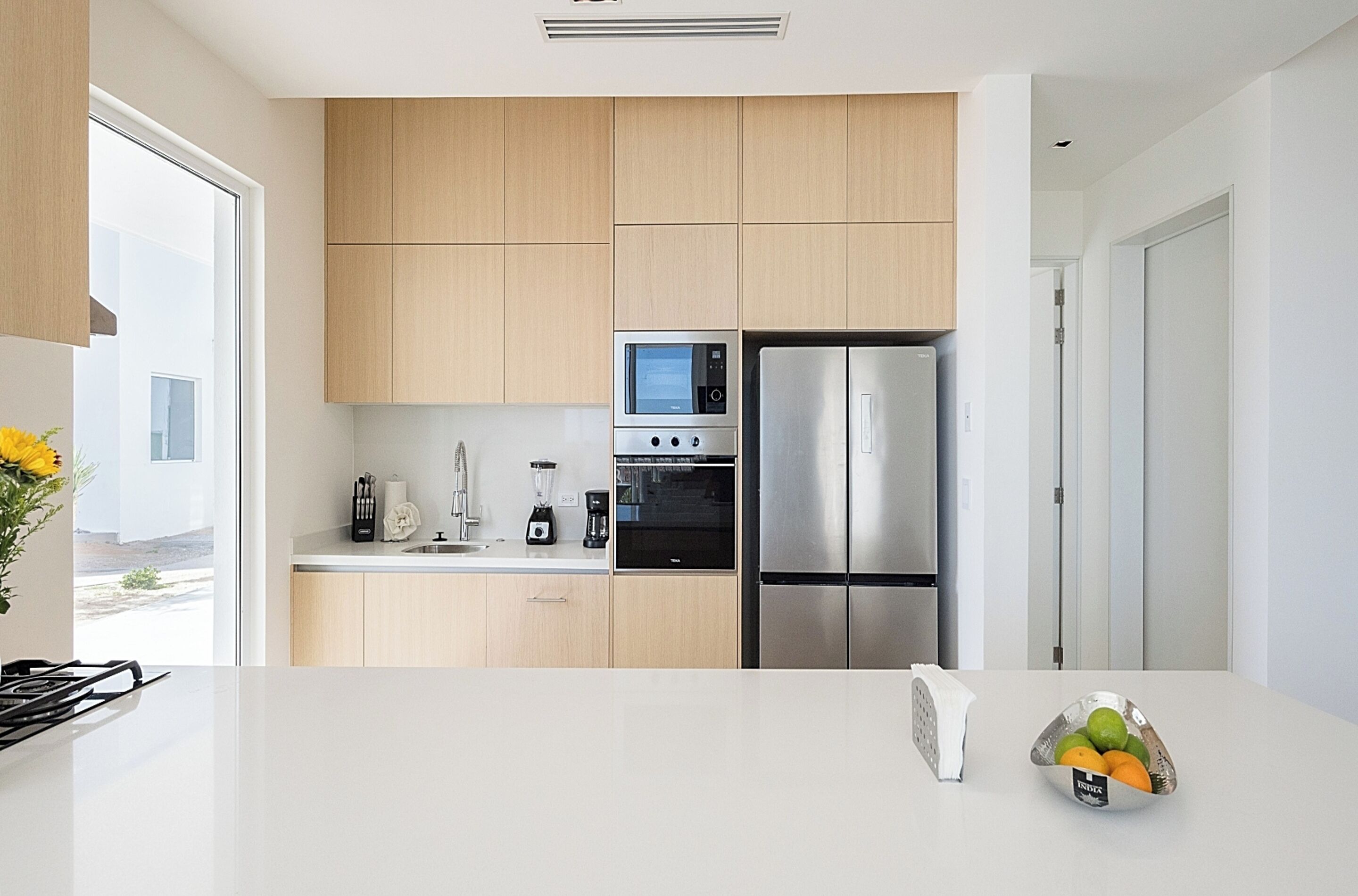 A modern kitchen with wooden cabinets, stainless steel appliances, and a white countertop.