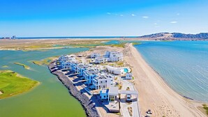 An aerial view of a coastal resort with modern buildings, a beach, and a marina. - Costa Divina A1 (Puerto Peñasco)