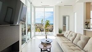 A modern living room with a large TV, a sofa, and a balcony with a view of the landscape. - Costa Divina A1 (Puerto Peñasco)