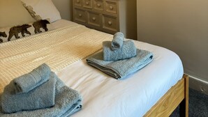 Un dormitorio con una cama, un tocador, un reloj y una obra de arte en la pared.