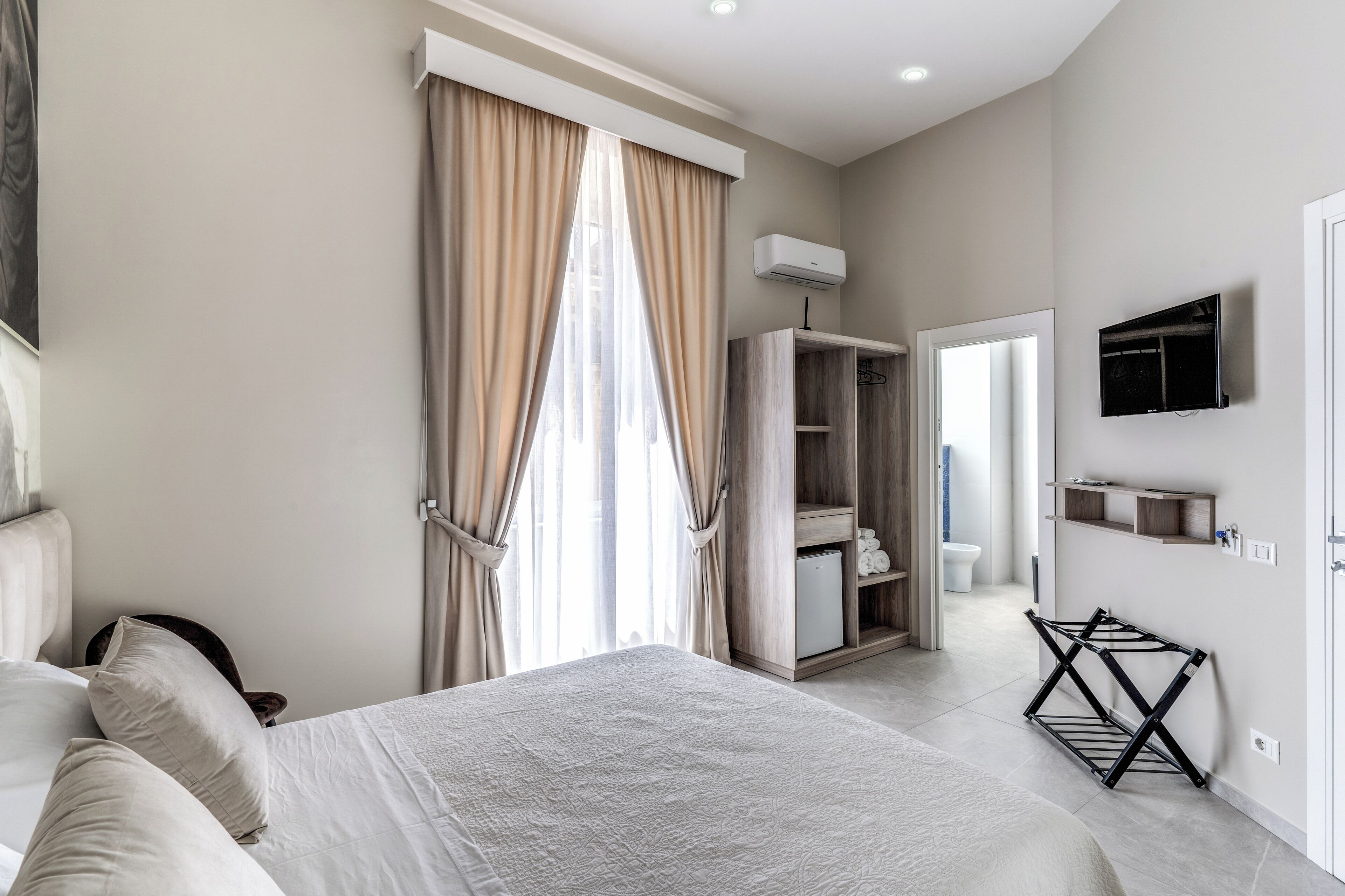 A bedroom with a bed, a wardrobe, a TV, and a drying rack.