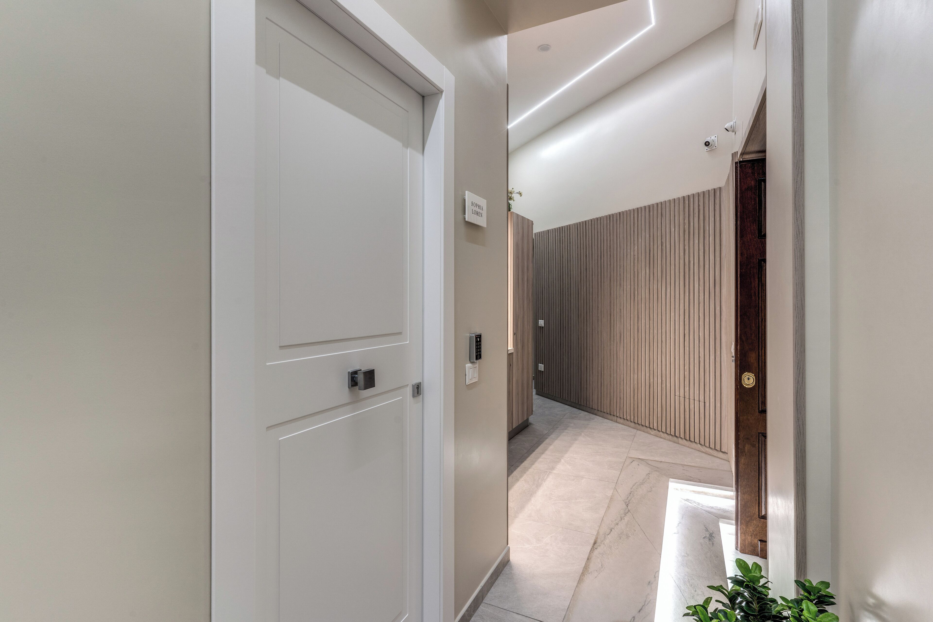 A modern hallway with a white door, a wall-mounted sign, and a wooden panel wall.