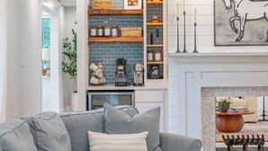 A modern living room with a grey sofa, a coffee machine, and a fireplace. - Family getaway.Commuter's Dream.Weddings&Events.Content House.Luxury Smart Home (Larchmont)
