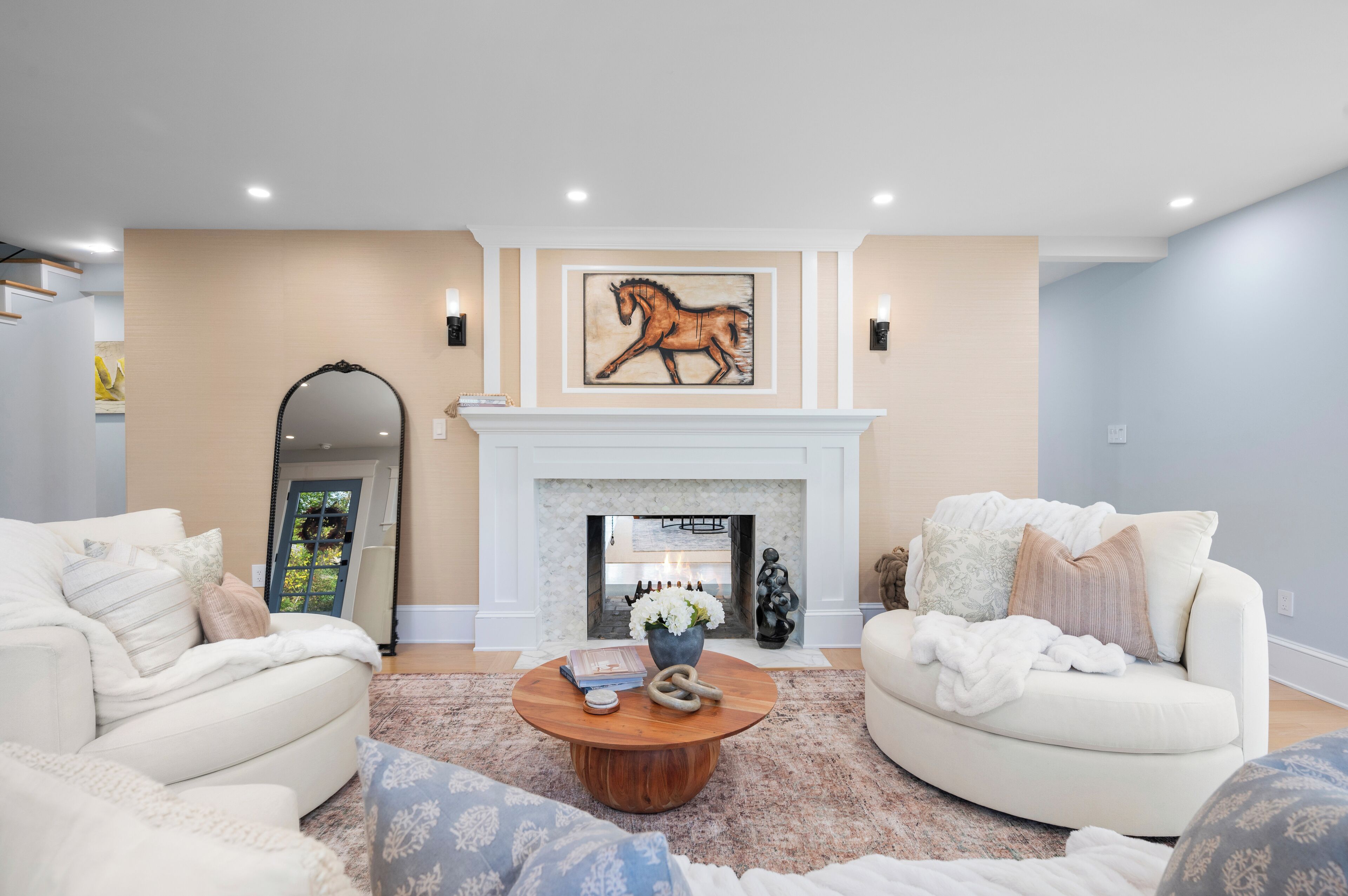 A living room with a fireplace, two sofas, a coffee table, and a mounted painting of a horse.