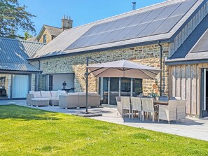 Un bâtiment en pierre doté d’un patio aménagé avec du mobilier d’extérieur et une table.