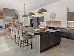 A modern kitchen with a central island, bar stools, pendant lighting, and a clock on the wall. - The Courtyard - UK47180 (Tanygroes, near Llangrannog)