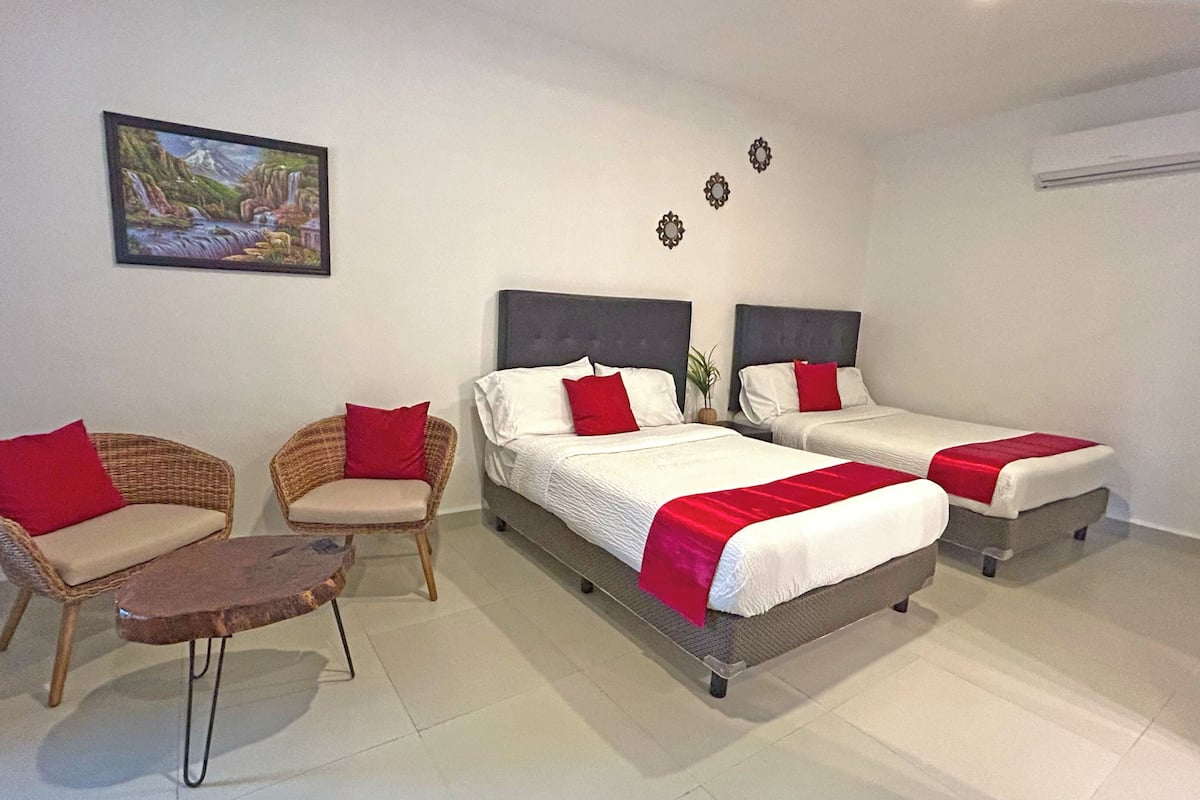 A hotel room with two beds, a sofa, a small table, and a painting on the wall.