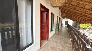 A corridor with a thatched roof, wooden doors, and a potted plant. - Soi Bacalar (Bacalar)