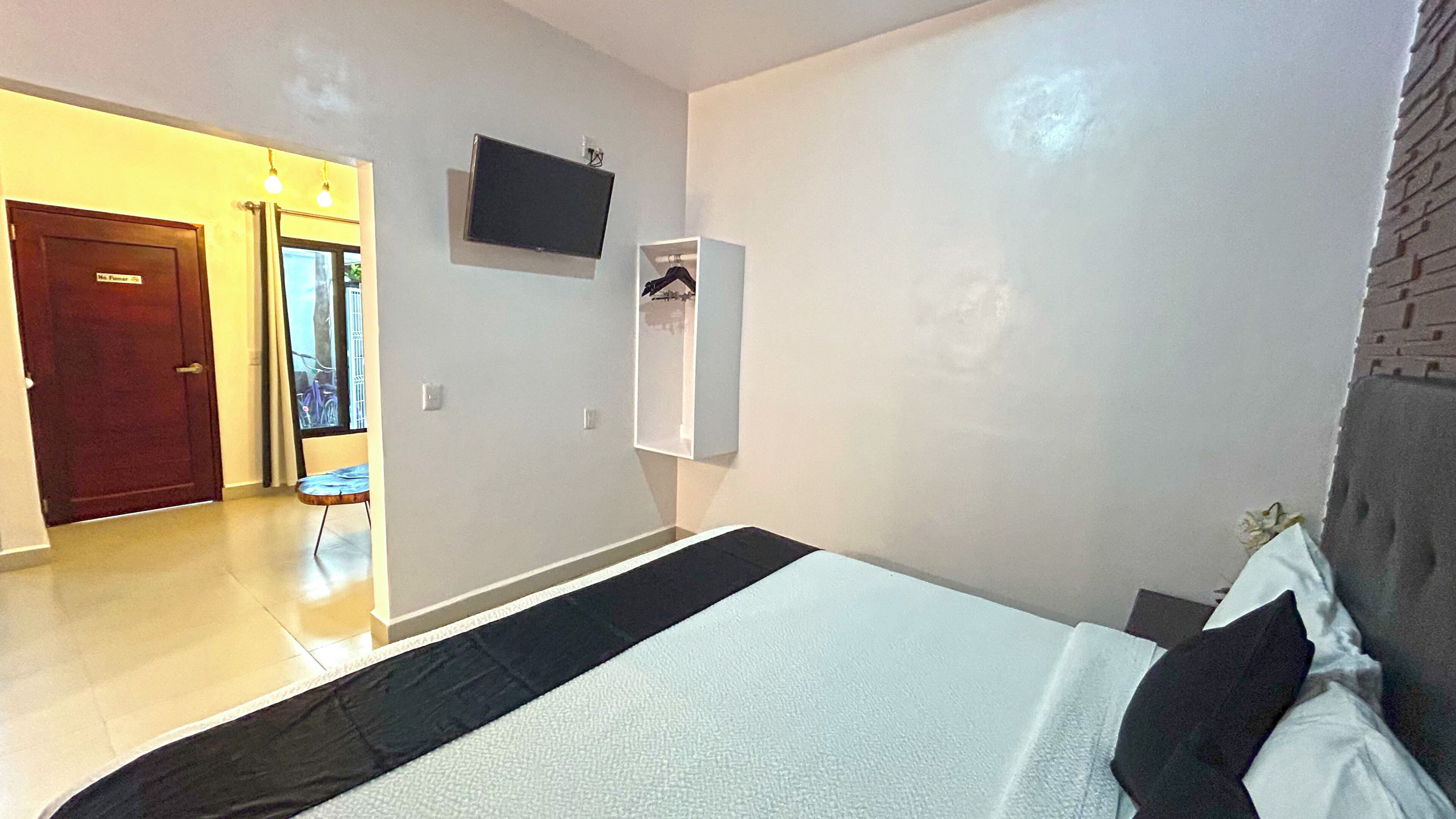 Ein Schlafzimmer mit einem Bett, einem an der Wand befestigten Fernseher und einem Kleiderschrank.