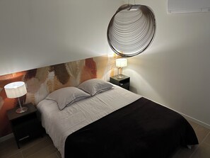 Una camera da letto con un letto, due comodini, una lampada e una parete con decorazioni a rilievo.
