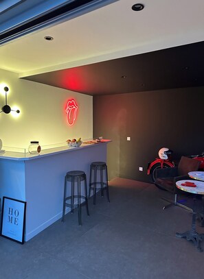 Et moderne barområde med en neonreklame, barstole, en motorcykel og et bord med en hjelm.