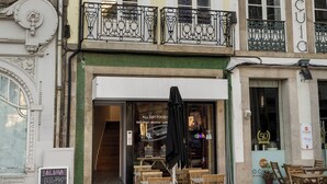 Un immeuble avec un café situé au rez-de-chaussée, des places assises en plein air et un escalier menant à l’étage supérieur.