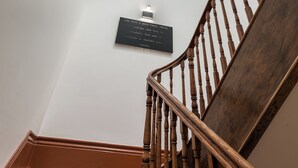 Un escalier en bois, avec un mur blanc et une lucarne.