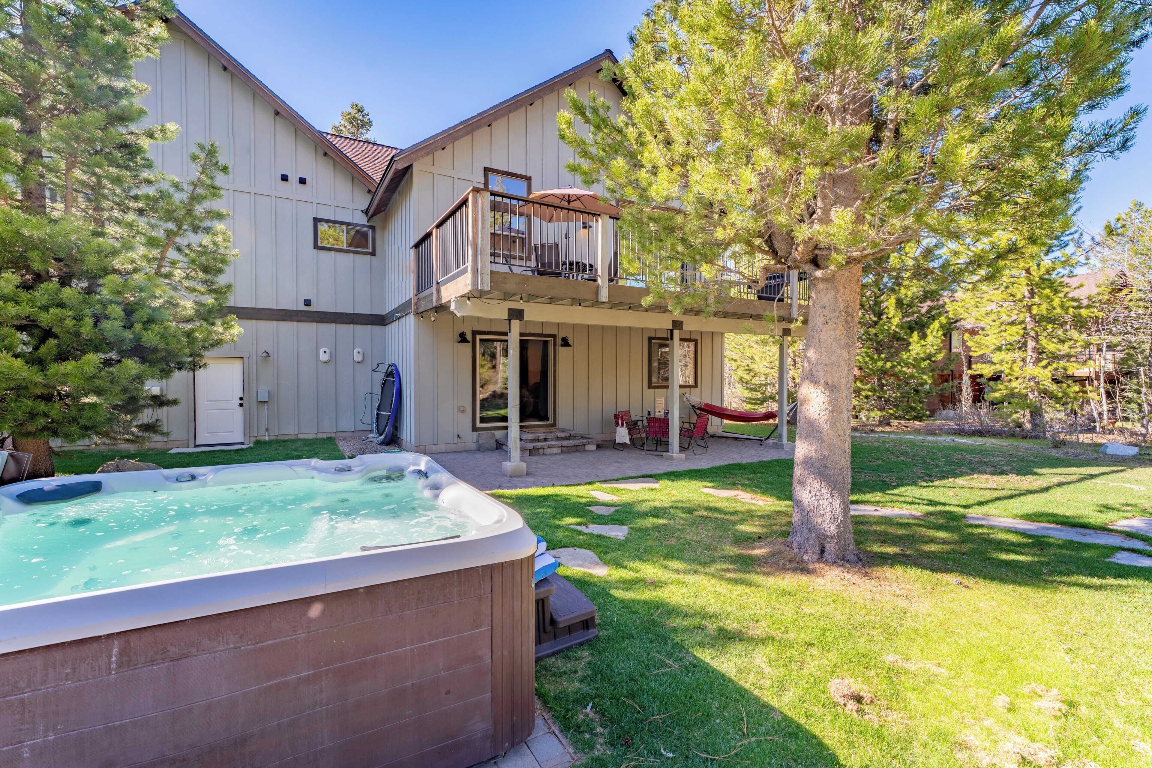 A two-story house with a hot tub in the backyard, a balcony, and a hammock.
