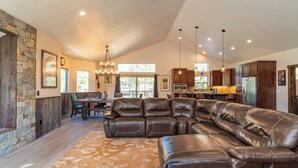 A spacious living room with a large leather sectional sofa, a dining area with a wooden table, and a kitchen with wooden cabinets. - 10mins to Lake Hot Tub, Game Room, Forest Views Meyers Meadow by Avantstay (South Lake Tahoe)