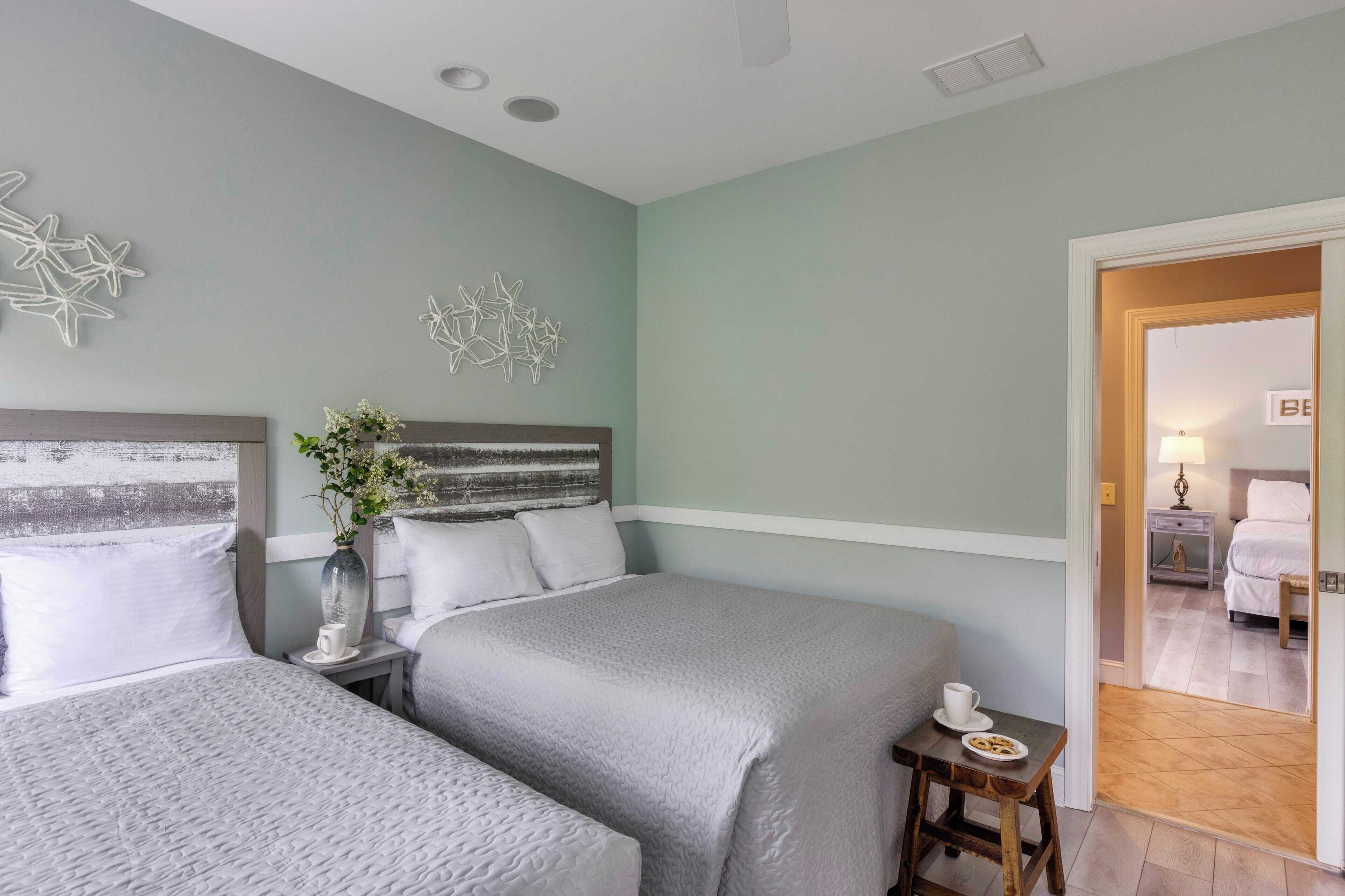A hotel room with two beds, a small table with a cup and plate, and a decorative wall piece.