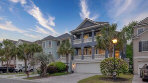 A multi-story residential building with a balcony, a driveway, and parked cars. - Crabline Getaway by Avantstay Private Pool + Hot Tub Easy Beach Access (Hilton Head Island)