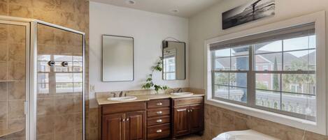 A bathroom with a walk-in shower, double sinks, a large mirror, and a bathtub.