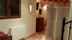 A hallway with a radiator, a wooden door, a woven mat, and a staircase with a black balustrade. - La Canal (Santillana del Mar)