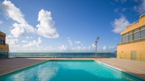 A clear blue pool with a view of the ocean and a clear sky.