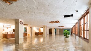 A spacious lobby with a marble floor, large windows, and a potted plant.