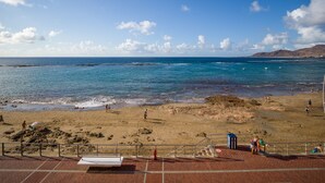 A beach with a clear sky, calm sea, and rocky terrain.