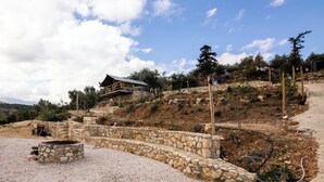 A stone staircase leading to a wooden deck with a metal railing, surrounded by a gravel area and a stone wall. - Glamping Chania - Secluded Oasis Among the Trees (Tsivaras)