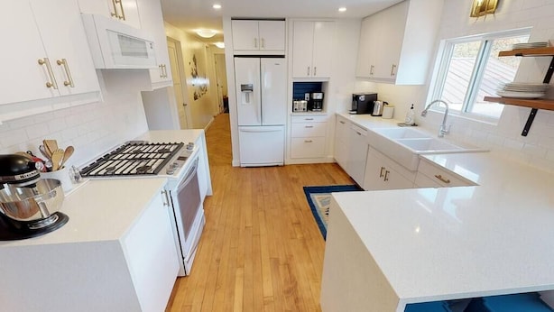 A modern kitchen with white cabinetry, a built-in oven, and a coffee maker. - ASPEN GROVE / Fernie / Hot Tub/ Walk Downtown (Fernie)
