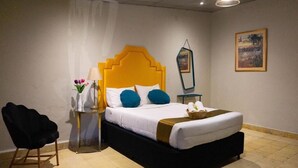 Ein Schlafzimmer mit einem Bett, einem Sessel, einem Nachttisch und einem Wandspiegel.