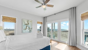 A bedroom with a large bed, a ceiling fan, and a view of the ocean through large windows. - 🏖️ Snowbird Beachfront Paradise-Incredible Views🏝️Lotsa Sand C (Gulf Shores)
